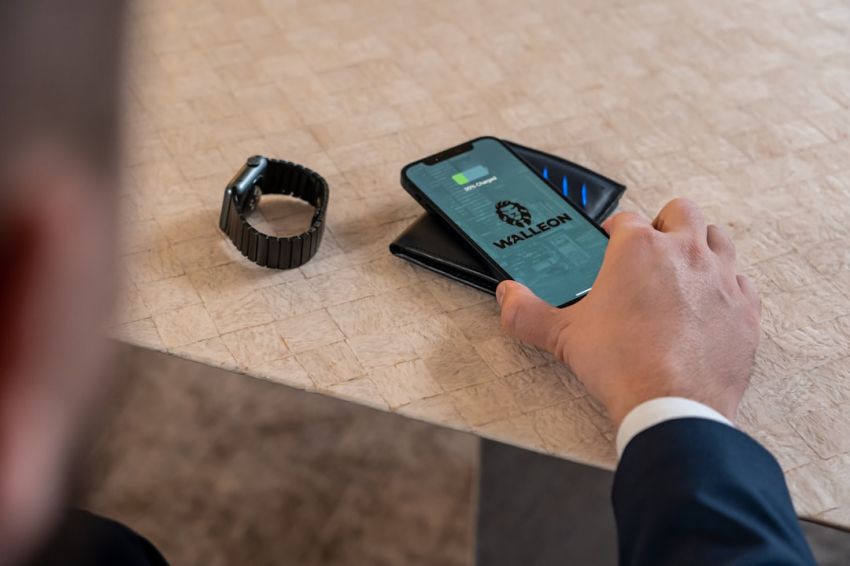 Wireless Charging - a man holding a smart phone next to a smart watch